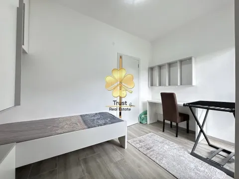 Small bedroom with a bed, desk, and shelving units. - image 6