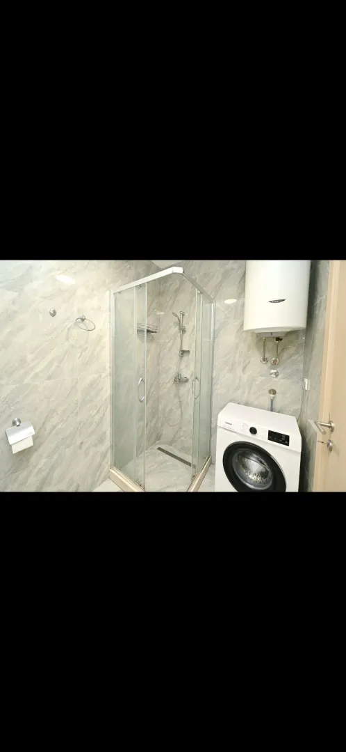 Bathroom with a shower cabin, water heater, and washing machine.