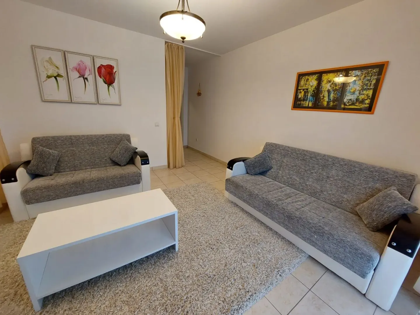 Dnevna soba sa garniturom za sjedenje, stočićem i slikama na zidu.