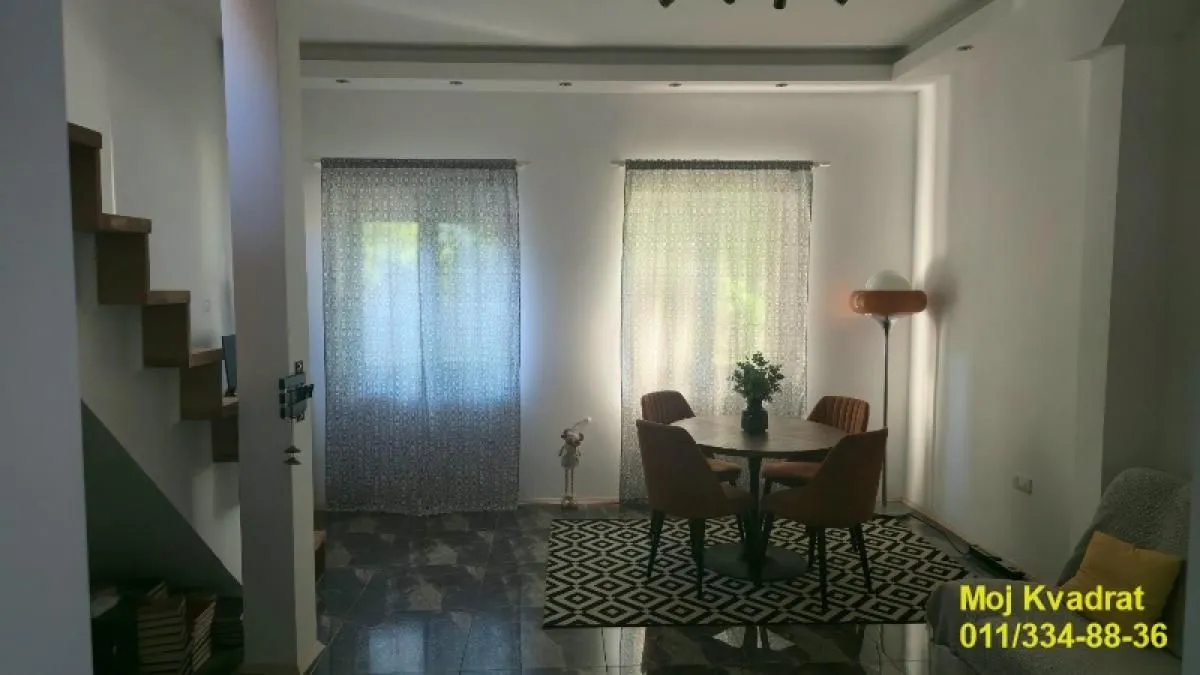 Dnevna soba sa trpezarijskim stolom i stolicama pored prozora.