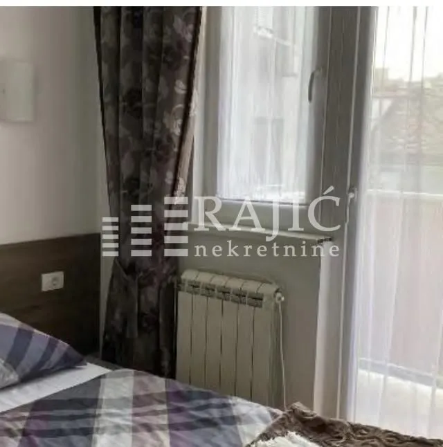 Part of a bedroom with a bed, window, and radiator.