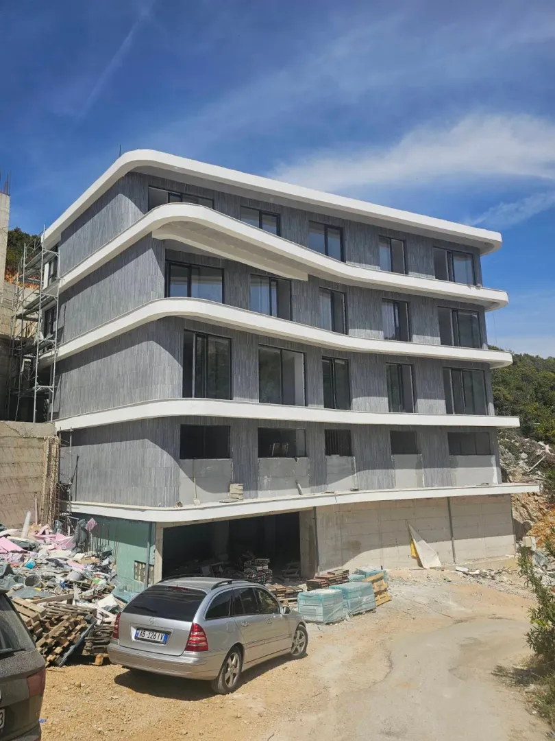 Exterior view of a multi-story residential building under construction with balconies and a gray facade.