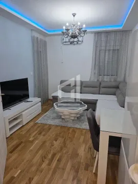 Living room with a sofa, TV, and dining table. - image 2