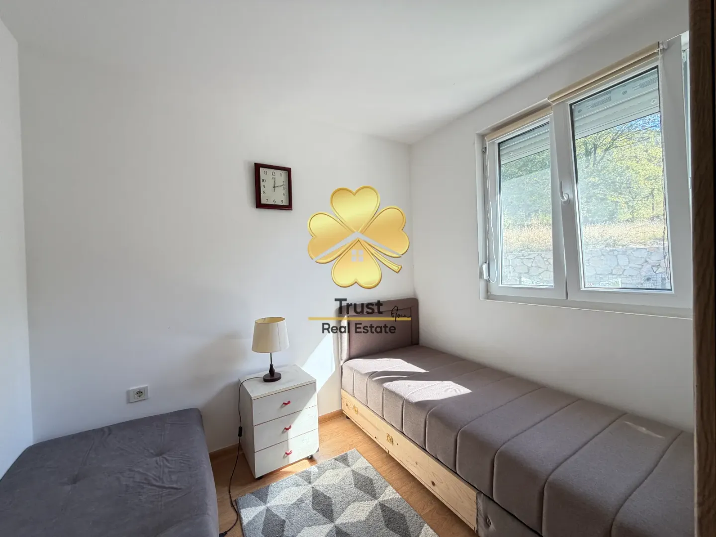 Small bedroom with two single beds, a nightstand, and a window.