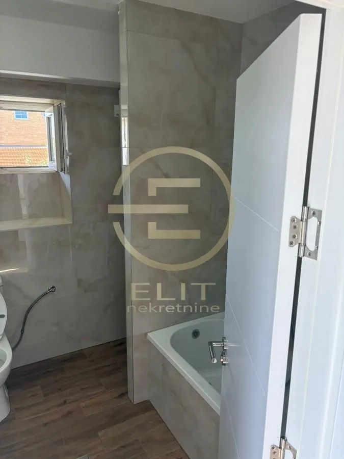 Bathroom equipped with a bathtub, ceramic tiles, and a window.
