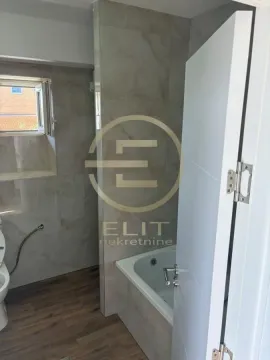 Bathroom equipped with a bathtub, ceramic tiles, and a window. - image 2