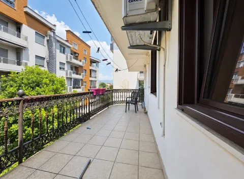 Long tiled balcony with a metal railing and a view of surrounding buildings and greenery. - image 4