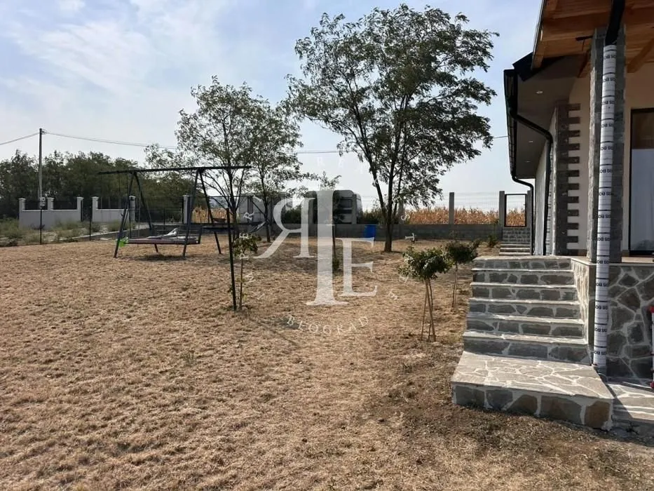 Spacious yard with lawn, trees, and a swing next to the house.