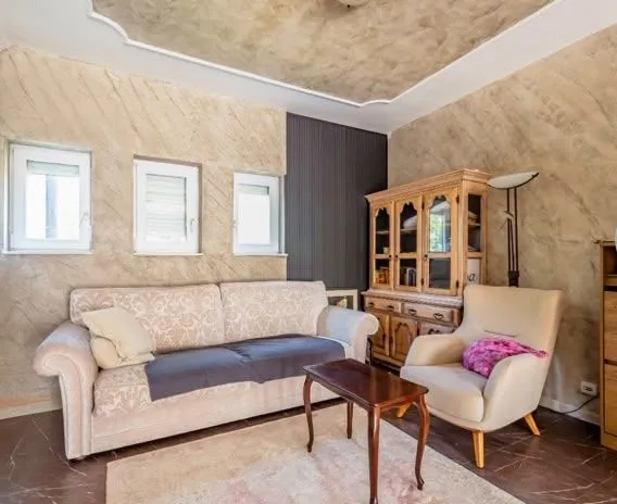 Living room with a sofa, armchair, and wooden cabinet.