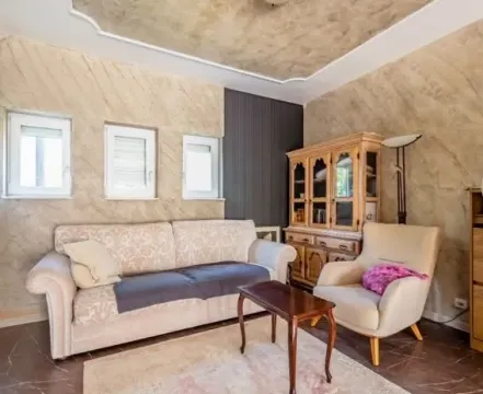 Living room with a sofa, armchair, and wooden cabinet. - image 4