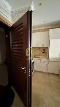 Pogled iz hodnika na manju kuhinju sa bijelim elementima. - image 17