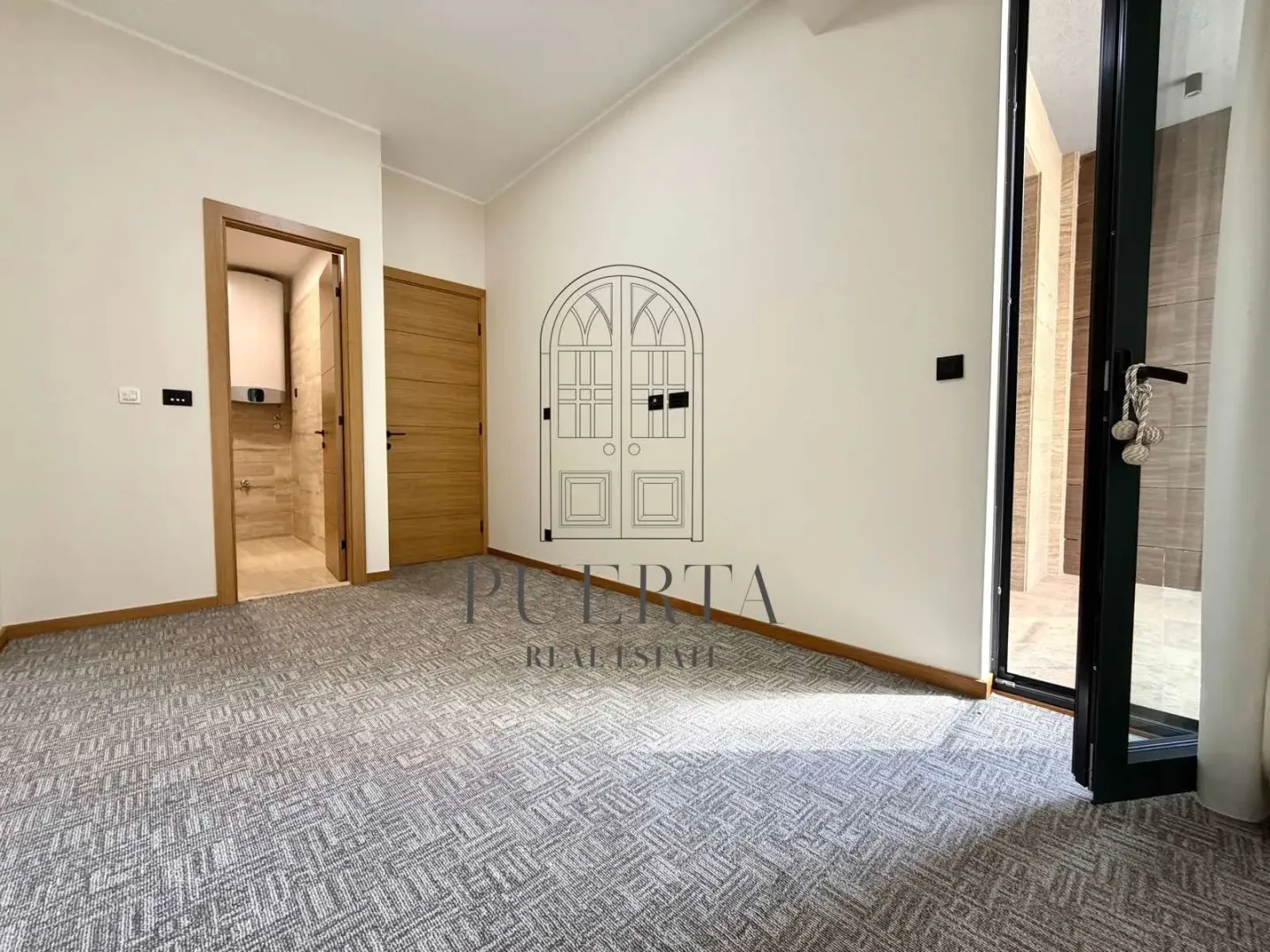 Empty room with grey carpet and wooden doors.