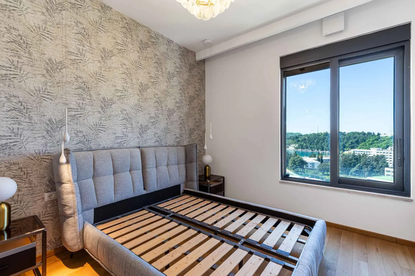 Svijetla spavaća soba sa modernim okvirom kreveta i lijepim pogledom.