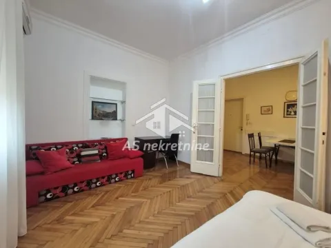 Bedroom with a bed, red sofa, and parquet flooring. - image 14