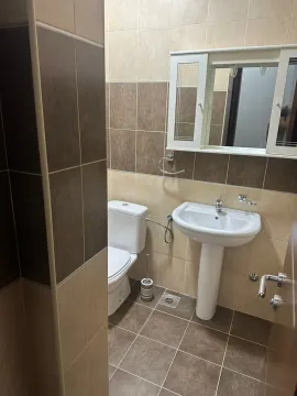 A bathroom with beige and brown tiles, a sink, and a mirror. - image 8