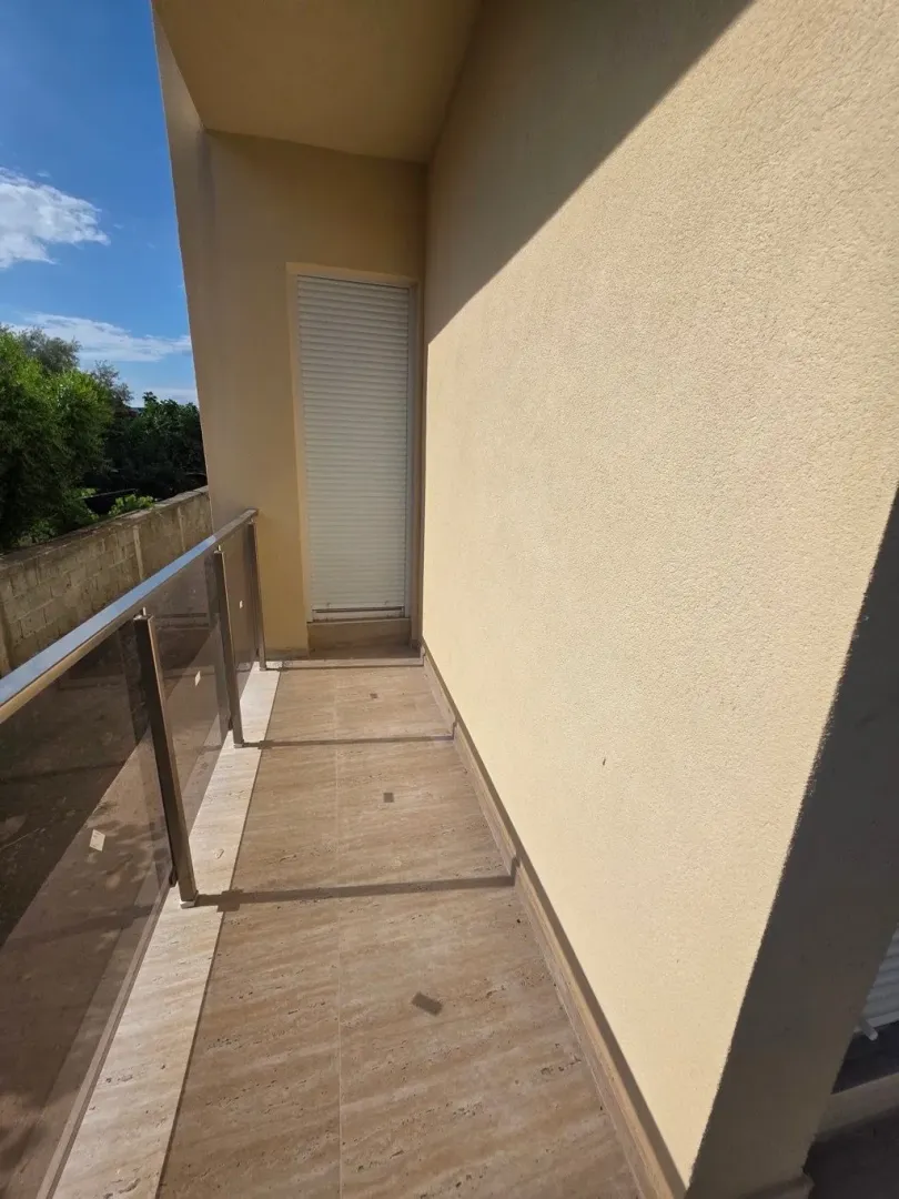 Prostrana terasa sa staklenom ogradom i popločanim podom.