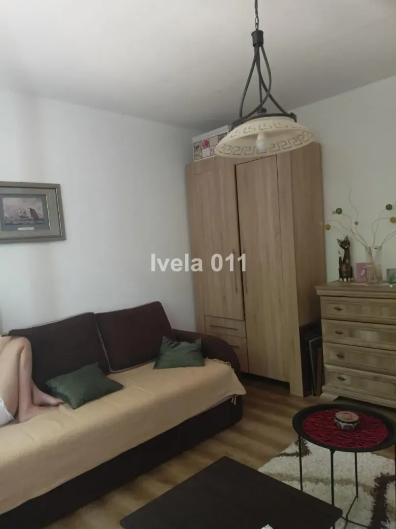 Dnevna soba sa garniturom, drvenim ormanom i komodom.