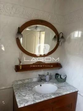Bathroom with a sink, wooden vanity, and a large wooden-framed mirror. - image 17