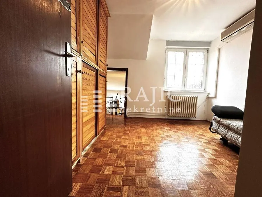 Small room with wooden flooring, a wardrobe, and a bed.