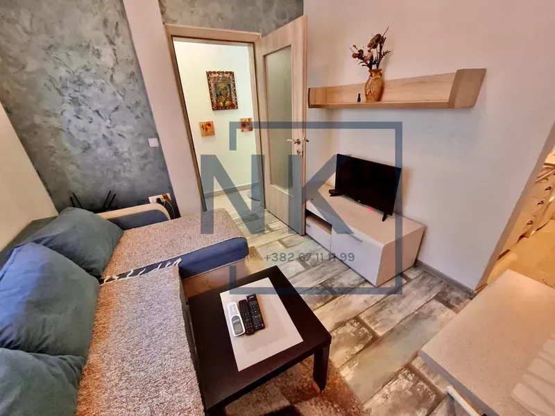 Manja dnevna soba sa ugaonom garniturom, televizorom i stočićem.