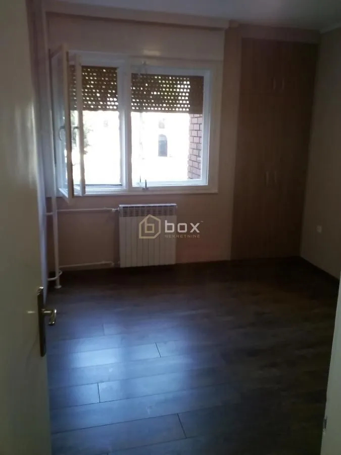 Empty room with a window, laminate flooring, and a built-in closet.