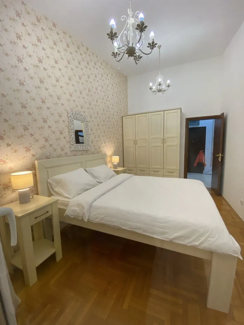 Bright bedroom with a double bed, wardrobe, and floral wallpaper.
