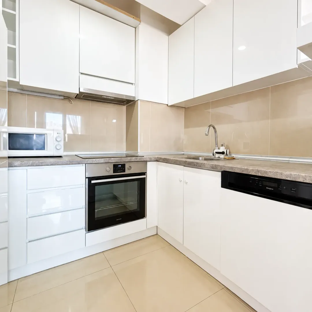 Modern white kitchen with built-in appliances and countertops.