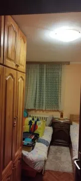 Manja spavaća soba sa dva kreveta i drvenim ormarom. - image 3