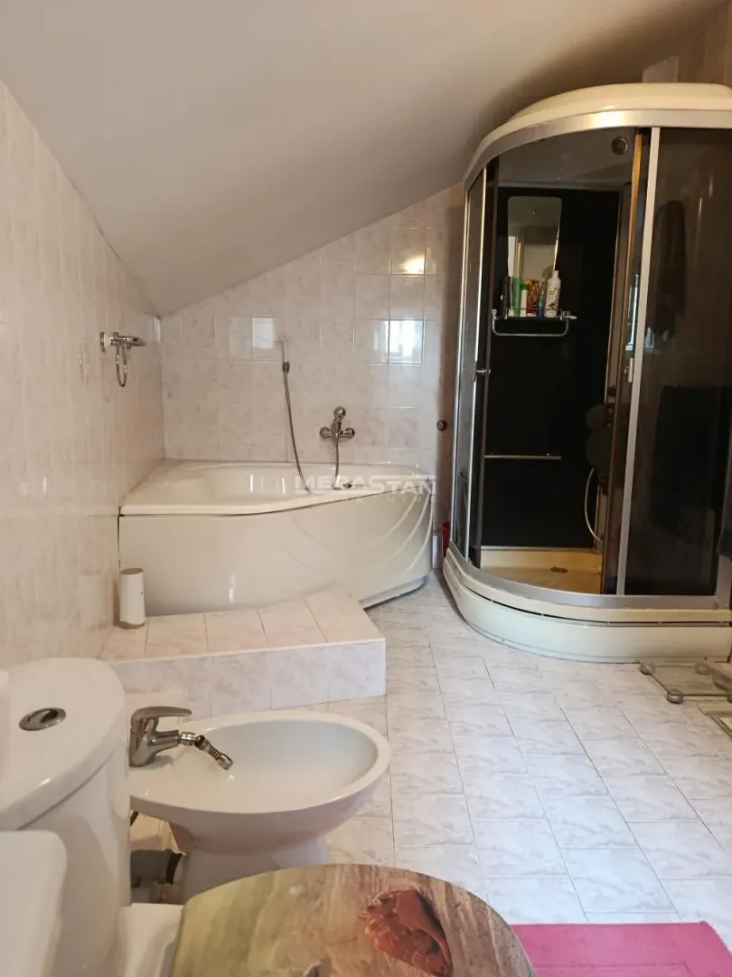 Bathroom equipped with a bathtub, shower cabin, toilet, and bidet.