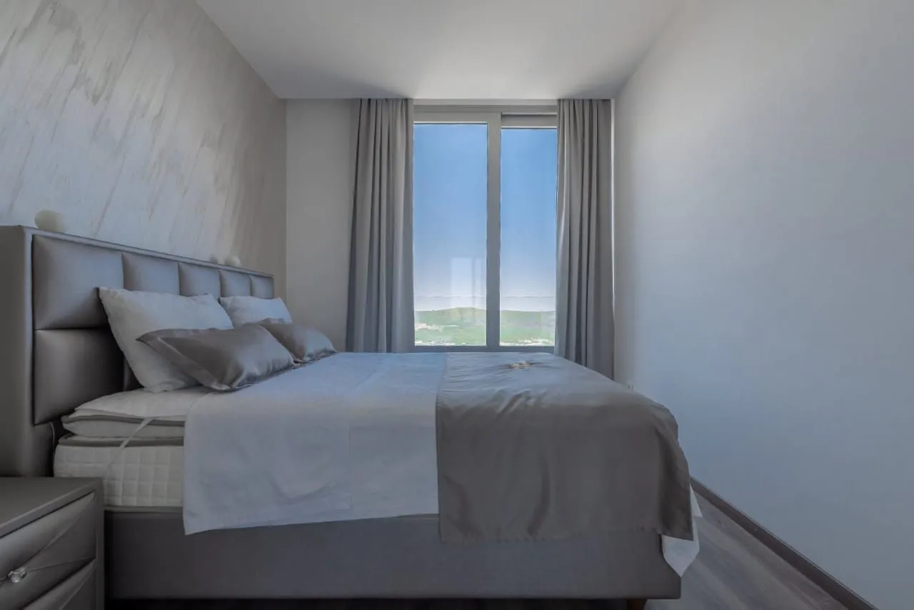 Modern bedroom with a double bed and a large window with a view of nature.