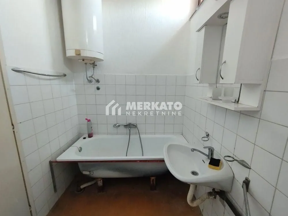 Manje opremljeno kupatilo sa kadom, umivaonikom i bojlerom.