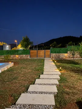 Illuminated courtyard with a walkway and entrance gate at night. - image 7