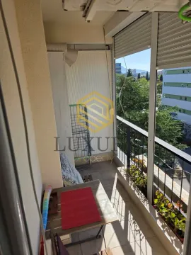 Enclosed balcony with a table and a view of surrounding buildings. - image 7