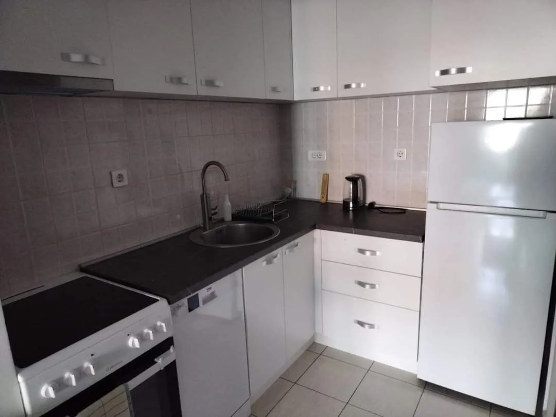 Small equipped kitchen with white cabinets and white appliances.