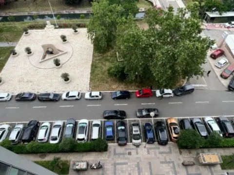 View from the apartment overlooking the street with parking and greenery. - image 12