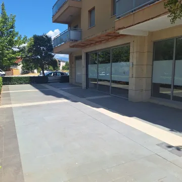 View of the building exterior with a paved platform and large glass display windows. - image 3