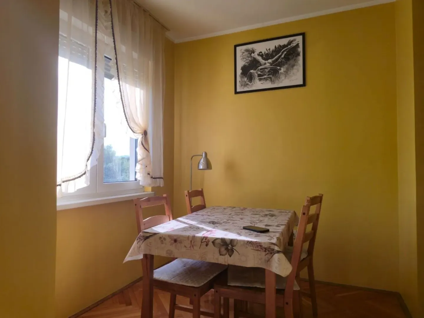 Dining area with a table, chairs, and a window against light walls.