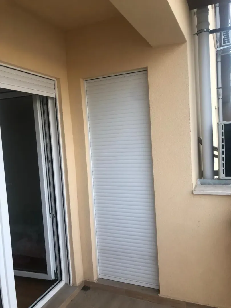 Balcony with a PVC door and a closed roller shutter.
