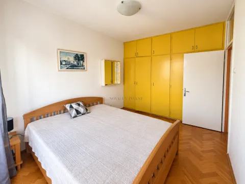 Spavaća soba sa bračnim krevetom, drvenim podom i žutim ugradnim ormarom. - image 7