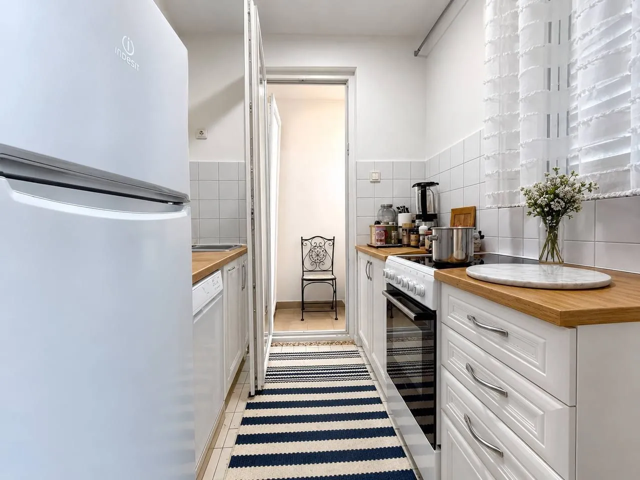 Small white kitchen with a wooden countertop and stove.