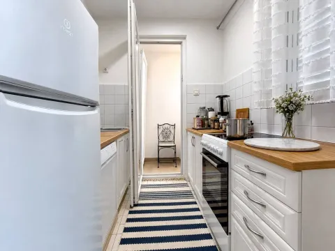 Small white kitchen with a wooden countertop and stove. - image 4