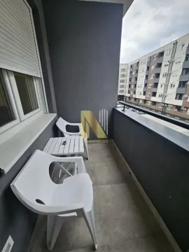 Manji namešteni balkonski prostor sa stolom i stolicama i pogledom na zgrade. - image 10