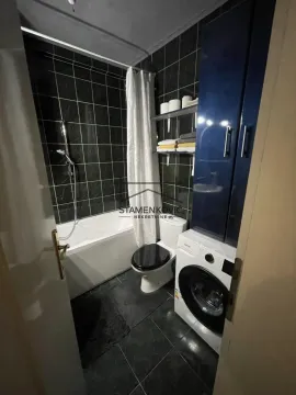 Kupatilo opremljeno kadom, toaletom, veš mašinom i plavim elementima. - image 7