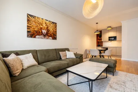 Spacious living room with a comfortable green sectional sofa and a dining area in the background. - image 3