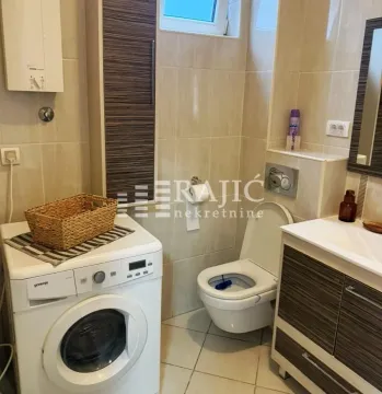 Smaller bathroom with a washing machine, toilet, and sink. - image 10