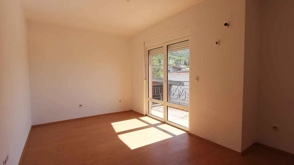 Prazna i svijetla soba sa izlazom na balkon.