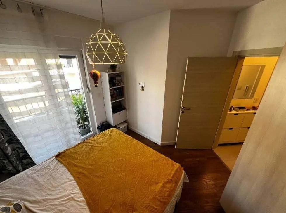 Namještena spavaća soba sa bračnim krevetom, balkonskim vratima i pogledom na kupatilo.