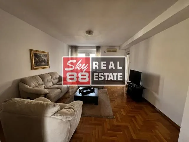 Dnevna soba sa garniturom za sedenje, stočićem i televizorom.