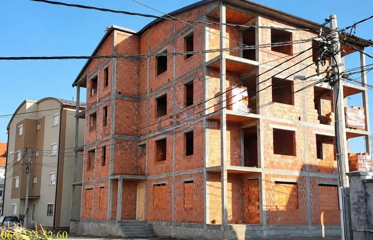 Exterior view of a multi-family residential building under construction with concrete structure and brick.