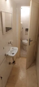 Small bathroom with a sink, mirror, and a separate toilet in the background. - image 11